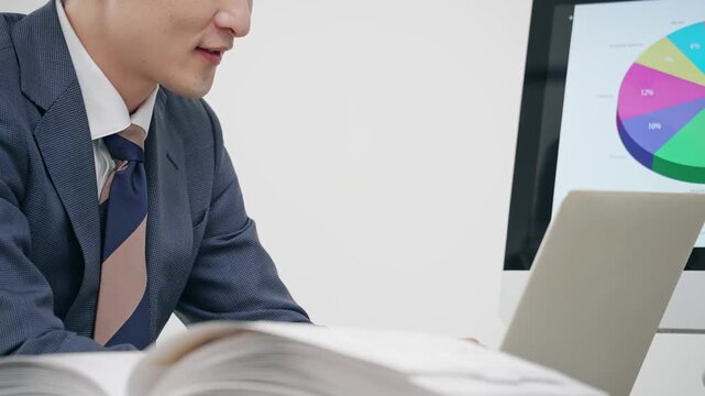 オフィスでPCを見ながら仕事する男性ビジネスパーソン