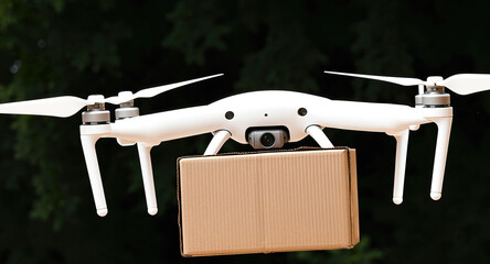 A delivery drone carries a cardboard box parcel