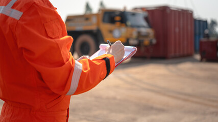 An operation supervisor is writing on paper during perform safety audit at construction work site,...