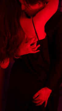 Caucasian couple engaging in foreplay under red light. 