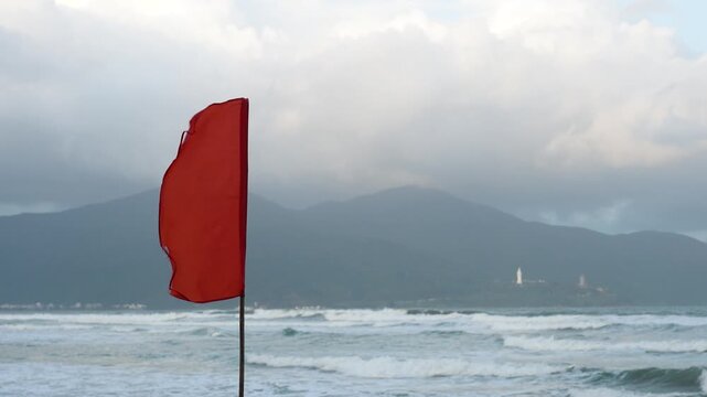 A red flag with heavy windy condition, it is the bad weather warning sign, do not swimming in the sea. Safety sign and symbol.