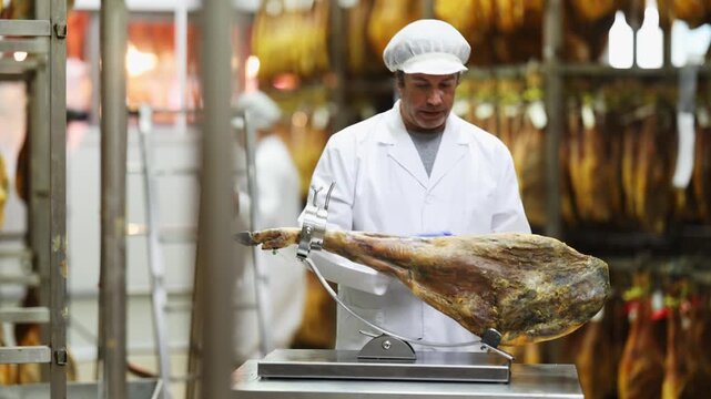  Man employee of hamon manufacturing workshop presents product using jamonero, and shows companys products from all sides