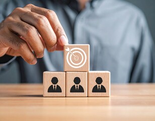 Hand places target cube atop employee icons, symbolizing success