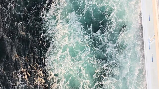 Ferry cruising through ocean waters near Osaka, Japan, with powerful prop wash creating churned liquid textures of foam and waves