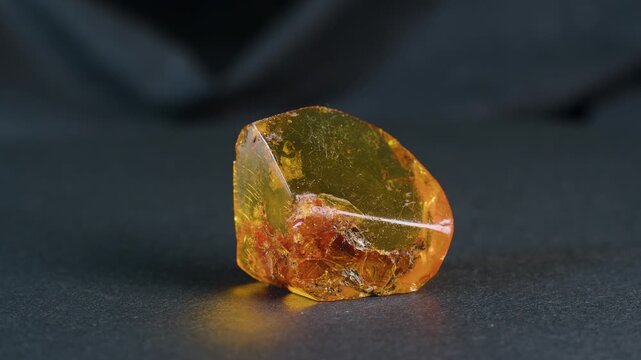 Faceted piece of natural Baltic amber on black background