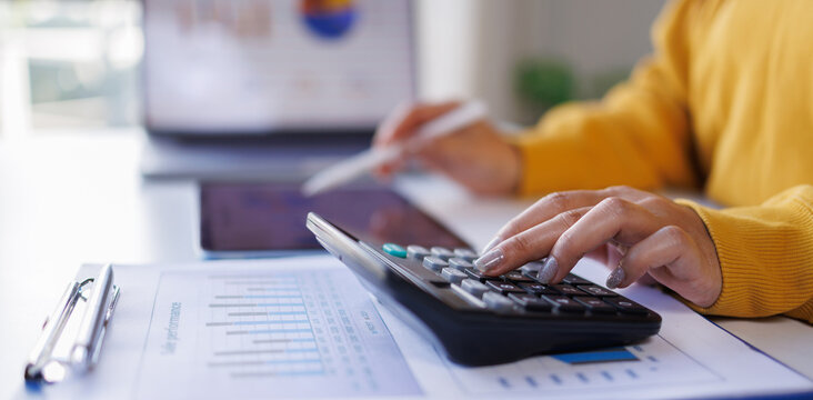 Business using calculator and laptop for do math finance on wooden desk in office and business working background, tax, accounting, statistics and analytical research concept
