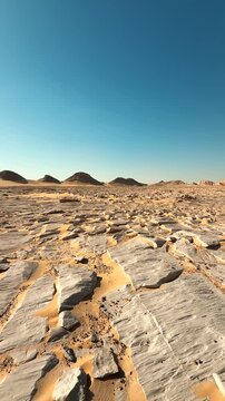 Vertical low angle vertical view of desert rocky ground. Motion along distant hills