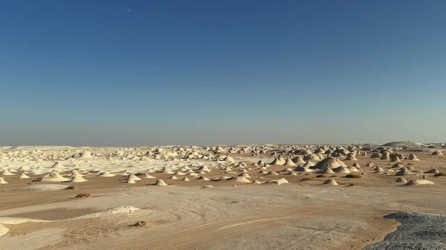 Plateau with chalk rock cone formations scattered in White Desert national park under blue sky