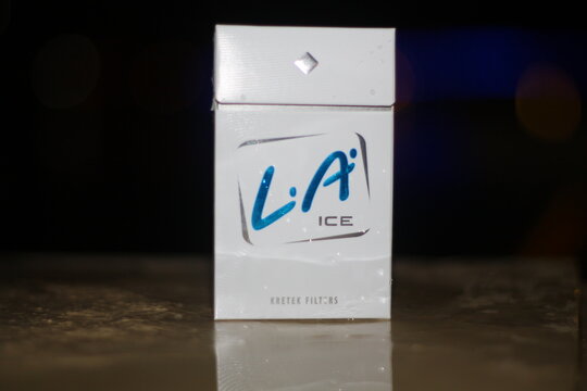 Editorial illustrative photo of a white pack of L.A. Ice kretek filter cigarettes placed on a wet surface with a dark bokeh background at night. South Kalimantan, Indonesia. July &lrm;13, 2013