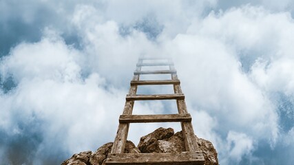 Wooden Ladder Reaching into Cloudy Sky Above Rocky Terrain with Soft Blue Background