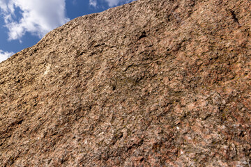 the texture of a red stone with multicolored inclusions, a stone with a rough structure of a red natural stone surface