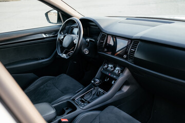 Modern interior of a family SUV, leather steering wheel, sports leather seats, large navigation screen. Interior details.