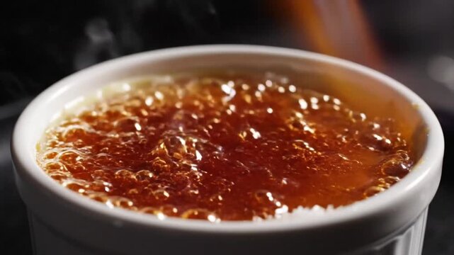 Chef carefully torches sugar on creme brulee to create a perfect caramelized crust in ramekin