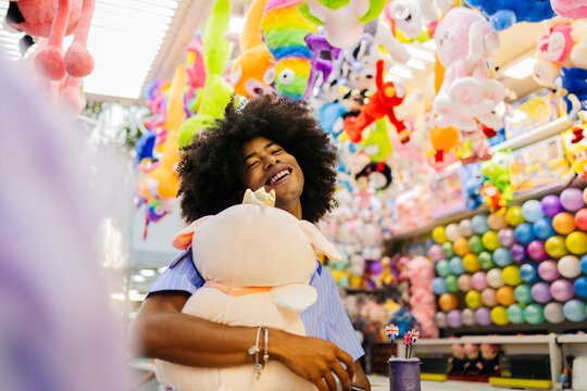 Smiling Afro man holding stuffed toy and standing near store