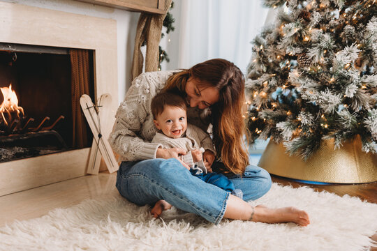 Mom and baby son playing by the fireplace.