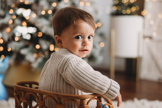 Baby boy with big eyes looking at camera with Christmas tree
