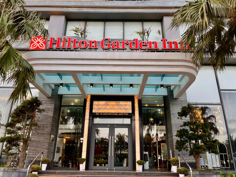 Da nang, Vietnam - February,10, 2026: A modern hotel entrance featuring glass doors and a large sign indicating "Hilton Garden Inn."