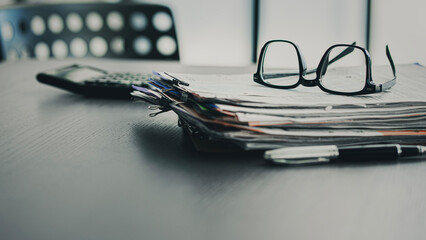 Pile of paperwork and calculator on office desk