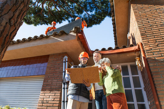 Engineer greeting senior homeowners during solar panel installation outdoors