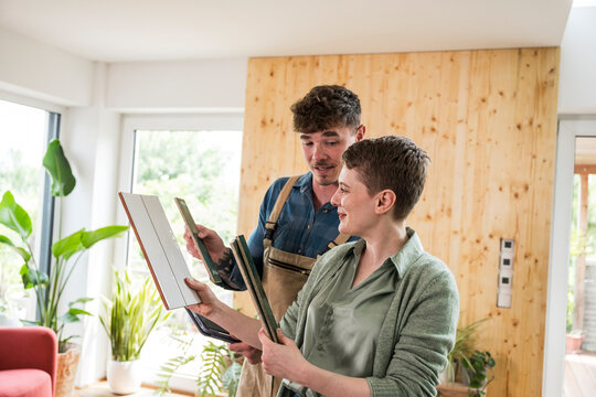 Craftsman and woman discussing renovation with tiles at home