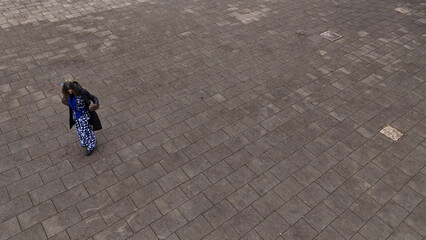 Overhead view of a woman in a patterned dress walking on a paved plaza © august.columbo