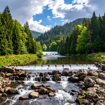River cascading over rocks and a small dam amidst a dense forest under a partly cloudy sky