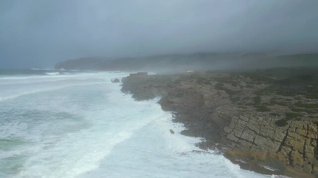 Flying over the sea of ​​Guincho and the coast on a stormy day Kristin with the rough sea and big waves on a cloudy and foggy day. Guincho beach,Cascais,Portugal