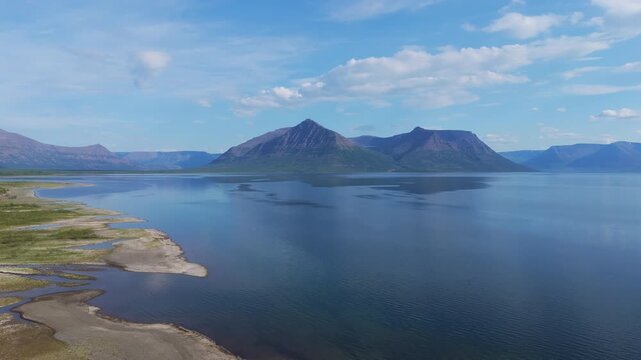 Midday clarity over Lake Lama with a mountain massif above mirror water on the Putorana Plateau. Sharp ridges, calm surface and broad shoreline convey wilderness and premium travel scenery in Siberia