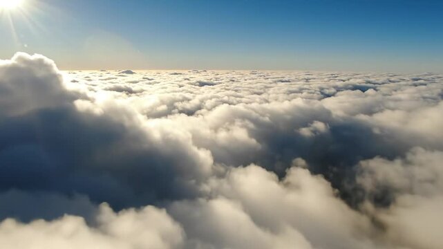 Bright sun shines above a vast expanse of f white clouds in a clear blue sky