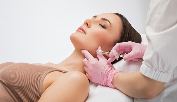 Cosmetologist makes rejuvenating anti wrinkle injections on the face of a beautiful woman. Female aesthetic cosmetology in a beauty salon.