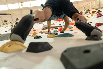 Excited moment Confident man enjoys indoor climbing as part of his urban fitness lifestyle. Asian male embracing rock climbing adventure sport workouts popular among the new generation.