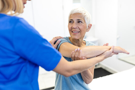 Senior Woman Doing Shoulder Stretch with Physiotherapist in Clinic. Healthcare and Medicine Concept. Happy Elderly Patient Recovering from Injury during Professional Physical Therapy Treatment.