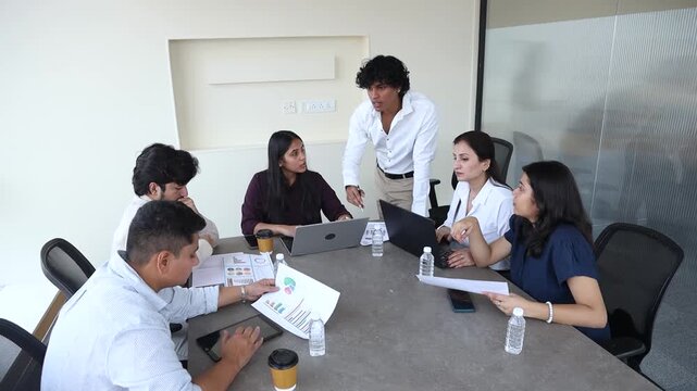 Young indian business or finance professionals conducting meeting in office conference room, discussing ideas and analyzing data for corporate growth and market strategy.