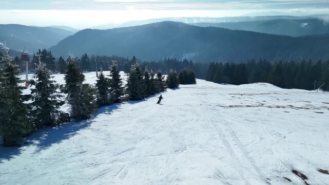Aerial Drone Footage of Skiers Descending Steep Mountain Slope at Alpine Ski Resort