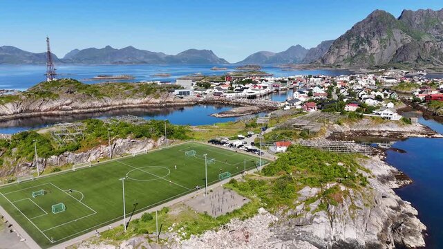 drone flight, at wonderful village Henningsv&aelig;r, Henningsvaer on many small islands. Famous soccer field visible. Some people playing on the field. Wonderful touristic travel destination on Lofoten isl