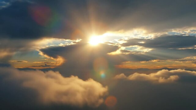 Epic sunrise sky with golden clouds and shining sunbeams, nature's light beams breaking through heavy cloud formations