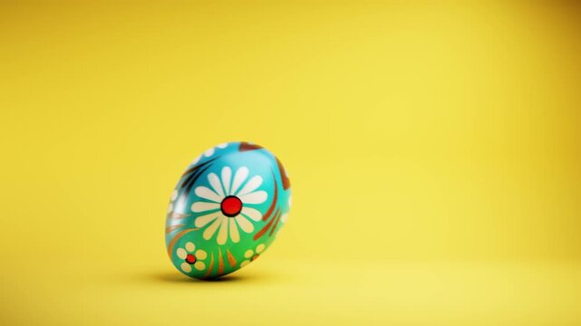 Hand painted Easter egg rolling on a vivid yellow background with copy space.