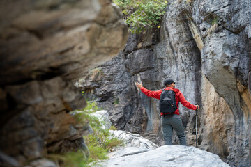 Hiker man climbing rocky mountain to explore hill and river enjoying outdoor adventure trekking, and nature travel. A true traveller and nature lover on an exciting hiking journey.