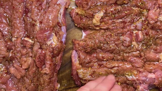 Preparing the turkey thigh for the roulade. The process: hand-roll the prepared piece of meat with spices on a wooden board.