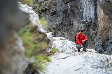 Hiker man climbing rocky mountain to explore hill and river enjoying outdoor adventure trekking, and nature travel. A true traveller and nature lover on an exciting hiking journey.