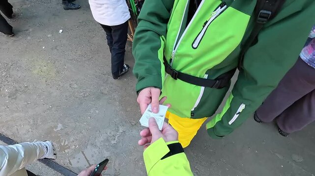 Authentic POV of a snowboarder climbing snowy stairs, getting a lift pass, and holding a board at a mountain ski resort. Candid winter lifestyle. Handheld