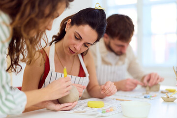 Friends Working Together Crafting Clay Sculptures in Bright Studio Workshop