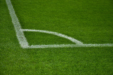 Obraz premium A close-up view of a vibrant green soccer field corner, highlighted by crisp white lines marking the boundary. Perfect for sports and nature enthusiasts.