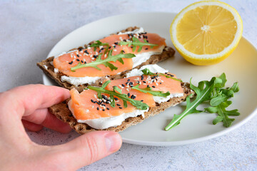 a person is holding a Smoked Salmon and Cream Cheese Crispbreads with Fresh Lemon