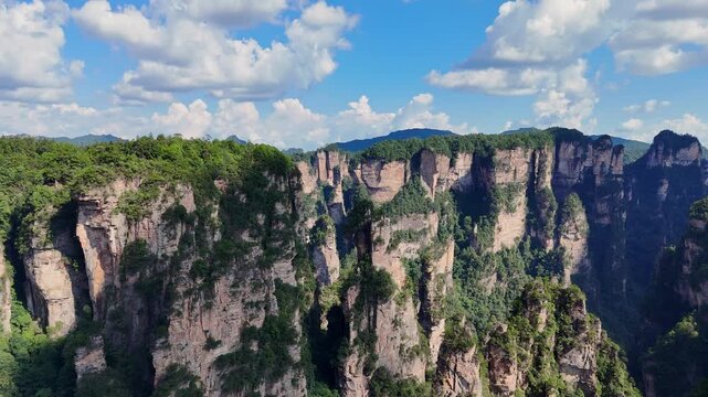 Iconic sandstone cliffs and pillars stretch across a lush subtropical landscape, aerial of Yuanjiajie Zhangjiajie China, establishing dolly