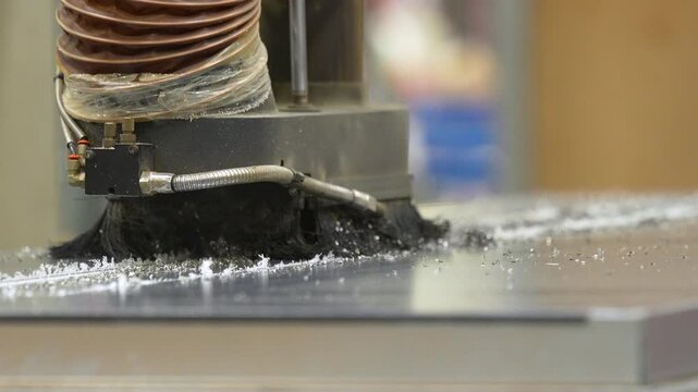 Close up of a CNC router bit with brush attachment carving through a wooden surface in a professional carpentry workshop.