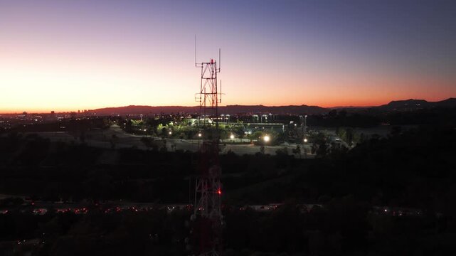 Low rising aerial shot of a transmission tower with Dodger Stadium in the background during twilight in Los Angeles, California. 4K
