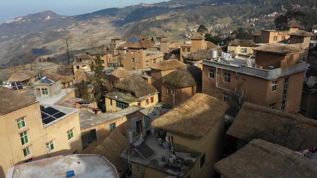 Drone shot over traditional homes with straw rooftops and newer developing buildings in Yuanyang rice terraces in China