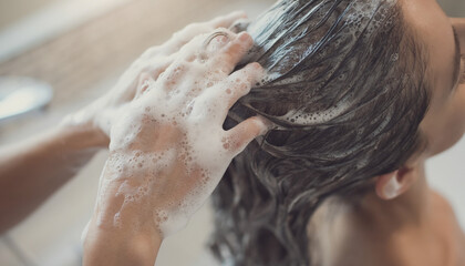 Person shampooing hair in bathroom with foam. Suitable for beauty, hygiene, hair care, and personal grooming concepts. Ideal for promotional material.