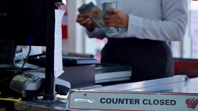 Counter closed sign on supermarket checkout desk with cashier holding cash in background, retail store register area during closing time, business and commerce concept
